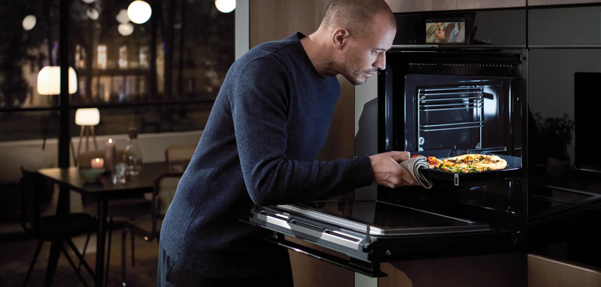 Man putting a pizza into an oven